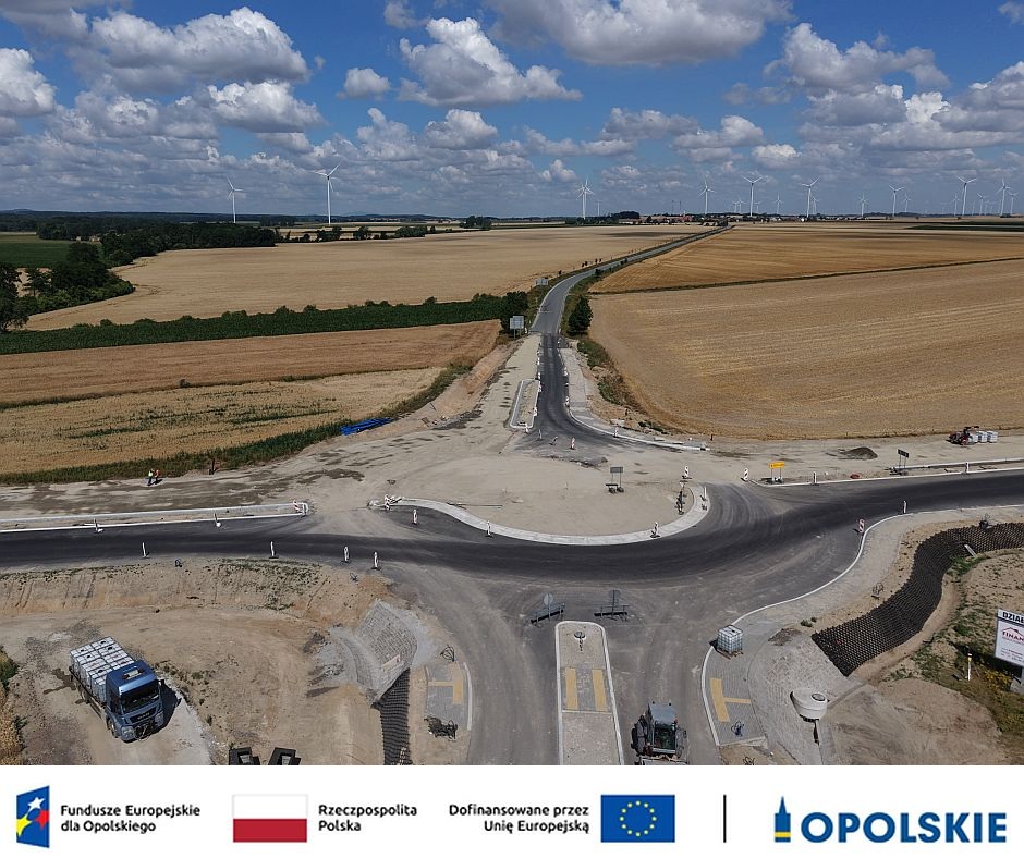 Widok z lotu ptaka na rozbudowywane skrzyżowanie drogi wojewódzkiej nr 401 na obwodnicy Grodkowa. Widoczne są nowe odcinki nawierzchni, prowadzone prace drogowe oraz otaczające inwestycję pola uprawne. Przedsięwzięcie dofinansowane ze środków Unii Europejskiej.